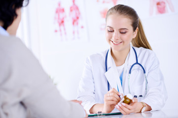 Female doctor prescribing medication for patient in medical office