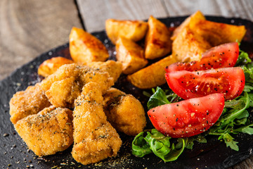 Fried chicken nuggets, baked potatoes and vegetable salad