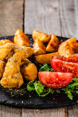 Fried chicken nuggets, baked potatoes and vegetable salad