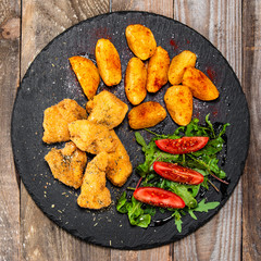 Fried chicken nuggets, baked potatoes and vegetable salad