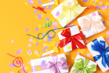 gifts, confetti and party accessories on a colored background top view.