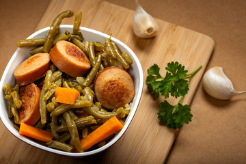 Stew made from green peas with pork sausages in bowl