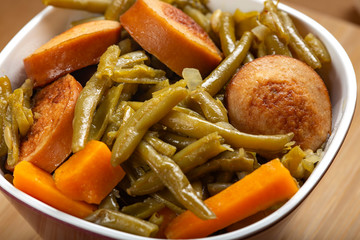 Stew made from green peas with pork sausages in bowl