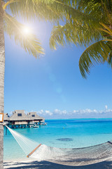 View of the sandy beach with palm trees and hammok, Bora Bora, French Polynesia