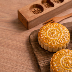 Round shaped fresh baked moon cake pastry - Chinese moonckae for Mid-Autumn Moon Festival on wooden background and serving tray, close up, copy space