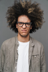 Fototapeta na wymiar Young curly displeased guy posing isolated over grey wall background.