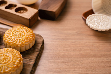 Round shaped fresh baked moon cake pastry - Chinese moonckae for Mid-Autumn Moon Festival on wooden background and serving tray, close up, copy space