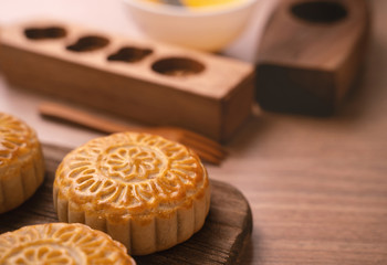Obraz na płótnie Canvas Round shaped fresh baked moon cake pastry - Chinese moonckae for Mid-Autumn Moon Festival on wooden background and serving tray, close up, copy space
