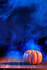 Halloween concept - Orange pumpkin lantern on a dark wooden table with double colored smoke around...
