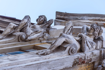 two statues of concrete adorn the facade of an old house