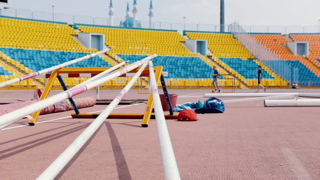 A stand in the stadium for the pole vault poles - people walking on the background