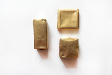 Chocolate candies wrapped in golden foil isolated on white surface. Template for greeting card,...