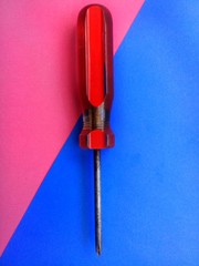 Old screwdriver with red handle and colorful background