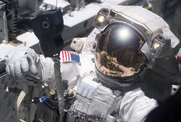 The astronaut in a space suit, in an outer space, is engaged in repair of the space station. ...