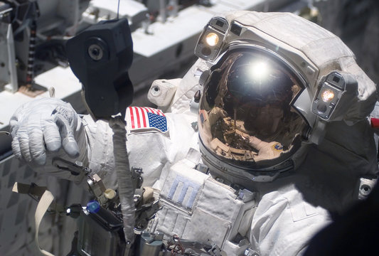 The astronaut in a space suit, in an outer space, is engaged in repair of the space station.  Elements of this image were furnished by NASA