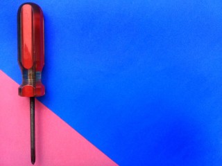 Old screwdriver with red handle and colorful background