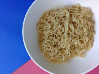 Ramen noodles in a white bowl with a colored background