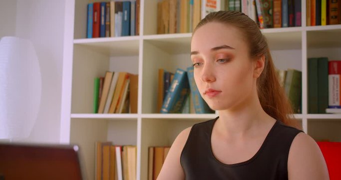 Closeup portrait of young successful redhead businesswomanusing laptop in office indoors