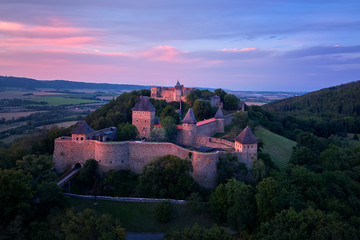 Helfstyn castle (German: Helfenstein, Helfstein), aerial view of a medieval gothic castle on a knoll over countryside. Castle walls in vibrant colors of setting sun. Czech landscape, Moravia region.