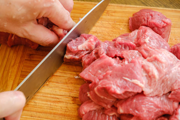 Butcher cutting pork meat on kitchen. Cut fresh meat with a knife.