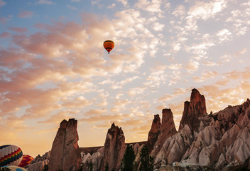 Fototapeta na wymiar Colorful air balloons fly up into the sky at sunrise among a beautiful rocky landscape. Cappadocia Turkey.