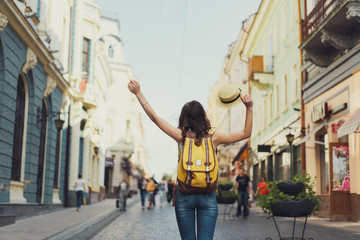 Back view of a young woman traveler with a backpack on her shoulder out sightseeing in a foreign...