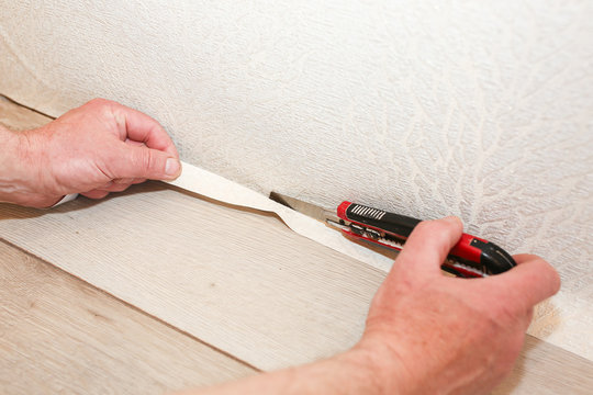 Man is cutting wallpaper. Maintenance repair works renovation in the flat. Restoration indoors.
