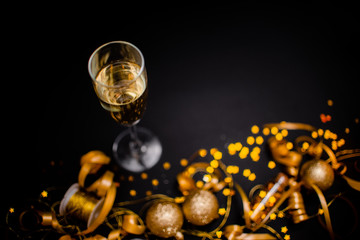 Gllasses of champagne on black stylish background with Place for text. Festive concept.Golden stylish decoration on black background.  Sticky tape, Christmas balls, golden ribbon