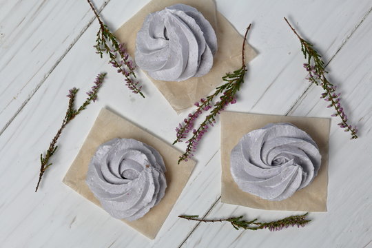 Freshly made lavender marshmallows on white painted boards. Heather branches are also visible. View from above.