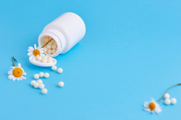 Homeopathy, naturopathy and alternative herbal medicine. Bottle with homeopathic pills and camomile flowers