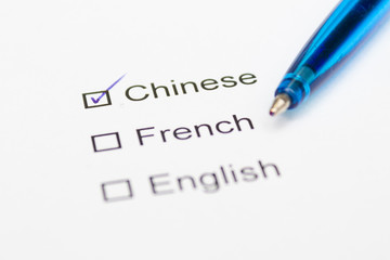 Chinese, French, English - checkmark with pen on paper.