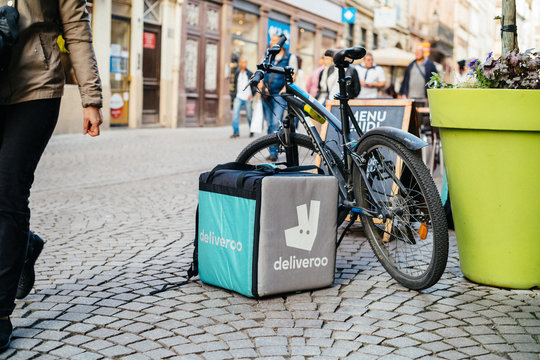 STRASBOURG, FRANCE - APR 3, 2017: Deliveroo cargo box near a parked bicycle with cafe terrace restaurant in the background to deliver on time the food to the client