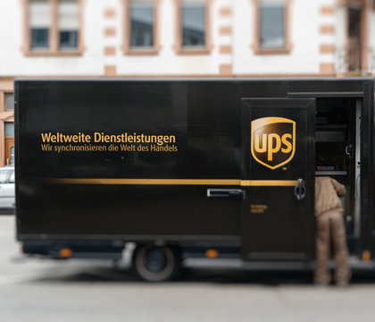 KEHL, GERMANY - APR 6, 2017: Worldwide delivery parcel - UPS United Parcel Service van delivery brown UPS van parked with driver worker searching for the parcel in the van interior - focus on logotype