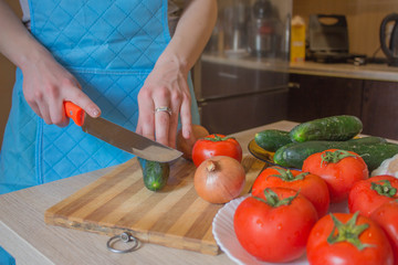 Woman's hands cutting vegetables, behind fresh vegetables. Woman cook at the kitchen