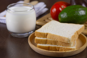 Sliced bread on wooden plate and fresh milk