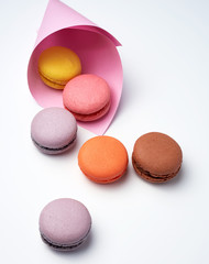 baked macarons in a pink paper bag on a white background