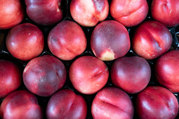 Fresh sweet ripe peaches on market stall as background