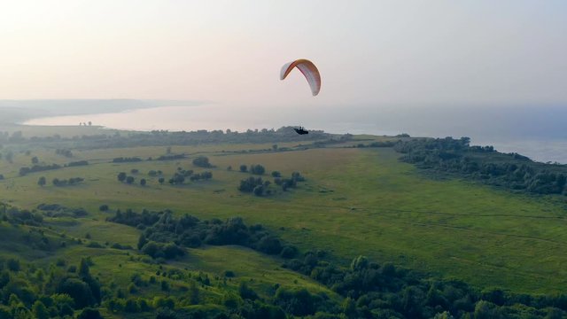 Parafoil is drifting above the fields and water