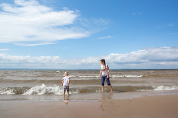 The child walks with his mother on the beach