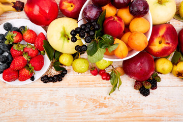 Flat lay of fruits over white wooden background, top view. Vegetarian, vegan, dieting, clean eating, weight loss ingredients.  Summer fruit food background. Copy space.