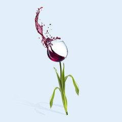 Glass of red wine with splashes as a flower on blue background. Bouquet of natural aromas in drink. Negative space. Modern design. Contemporary art collage. Concept of alternative view of usual things