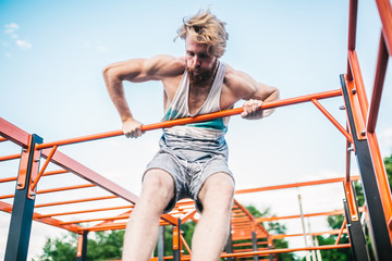 strong athlete doing pull-up on horizontal bar. Muscular man doing pull ups on horizontal bar in...