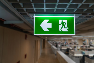 Green fire escape sign hang on the ceiling in the office.