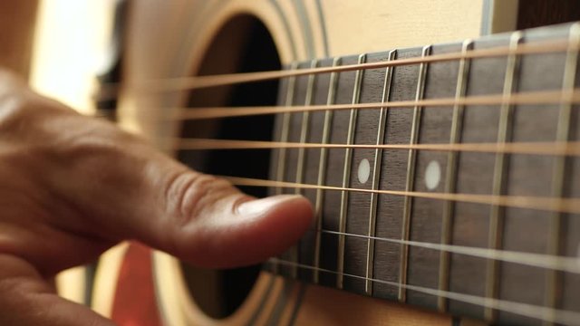 Close up. The fingers of the musician to touch the strings of the guitar. A man plays an acoustic guitar. Music and Hobbies.