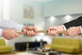 Business people pulling rope in opposite directions at office