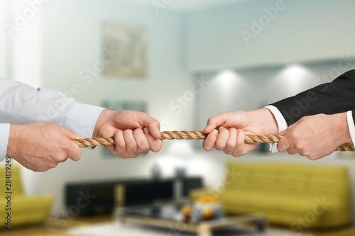 Business people pulling rope in opposite directions at office