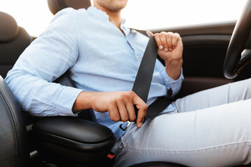 Cropped photo of young man wearing seat belt while driving convertible car