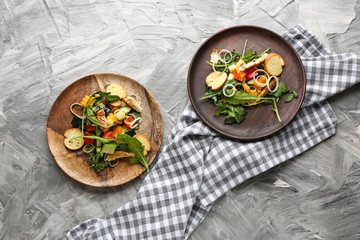 Plates with tasty arugula salad on grunge background