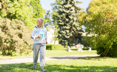 fitness, sport and healthy lifestyle concept - senior woman running along summer park