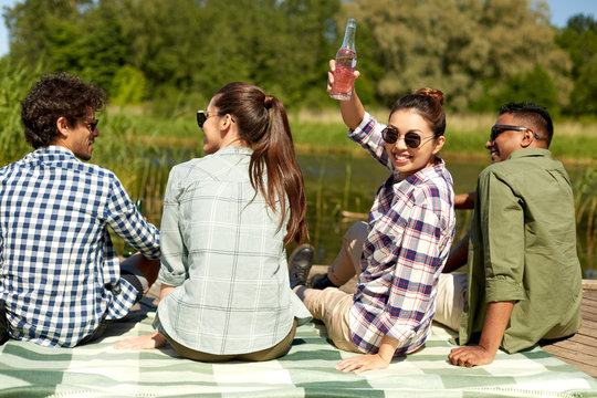 leisure, picnic and people concept - happy young asian woman friends with on lake pier in summer toasting drink - Powered by Adobe